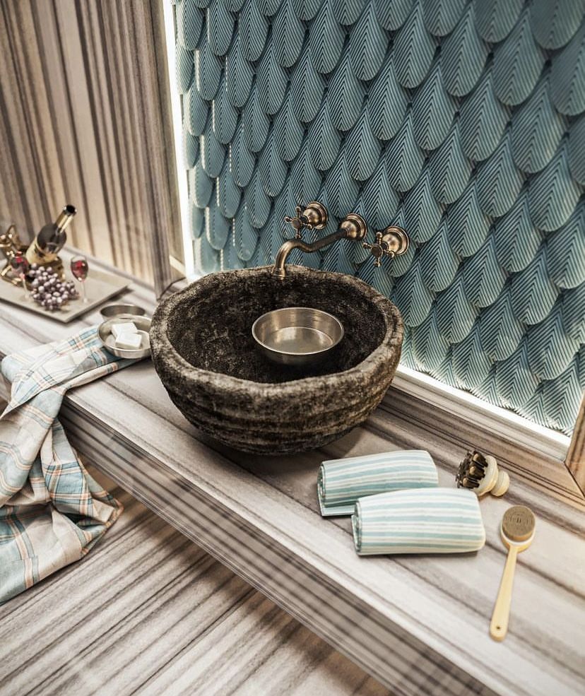 Turkish hammam detail with a natural stone basin and traditional metal brassware